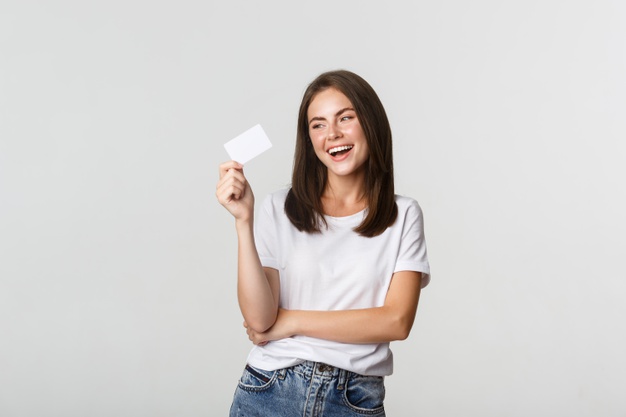 mulher de jeans azul e camiseta branca segura um cartão e sorri