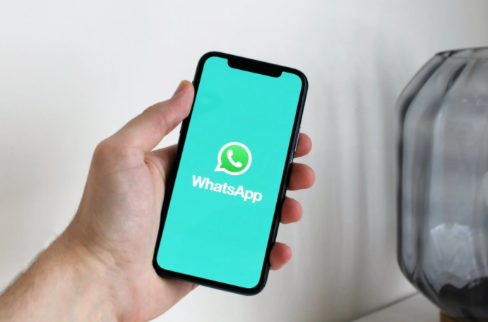 pessoa segurando um celular com o ícone de whatsapp na tela