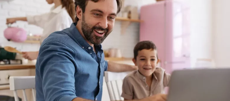 pai e filho mexendo no computador enquanto mãe cozinha - empréstimo bolsa família quando vai ser liberado