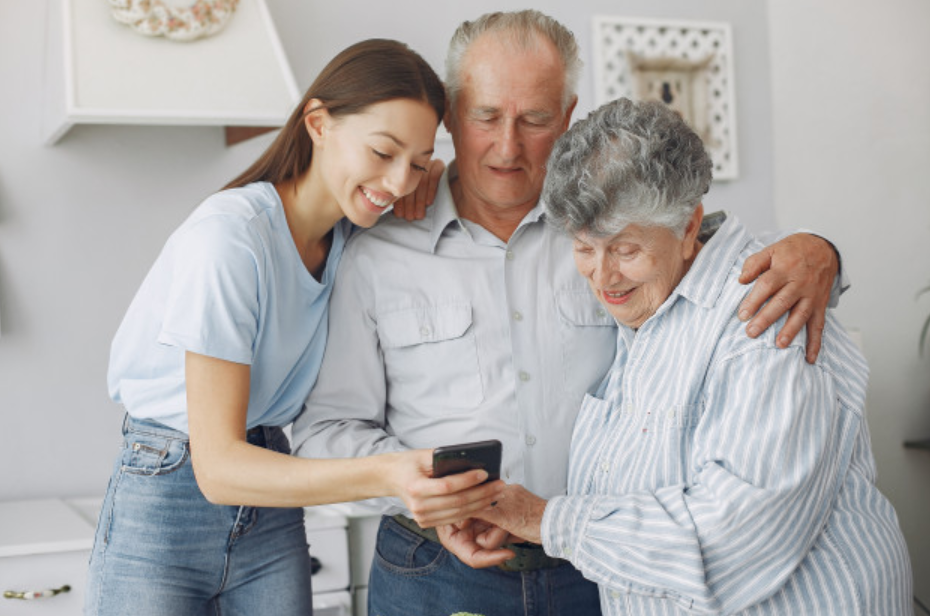menina de azul mostrando aparelho celular para os seus avós dentro de casa