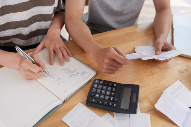 duas pessoas calculando contas com caderno e calculadora.