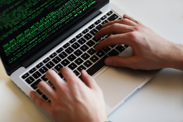 imagem ampliada de um homem teclando em um laptop cinza com teclado preto