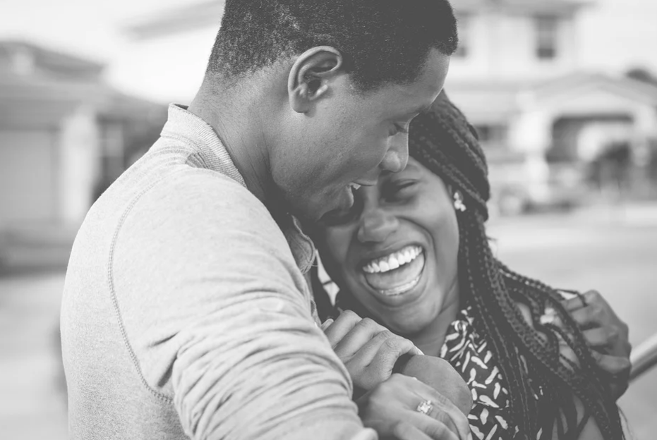 Imagem em preto e branco de um casal que se abraça e sorri feliz