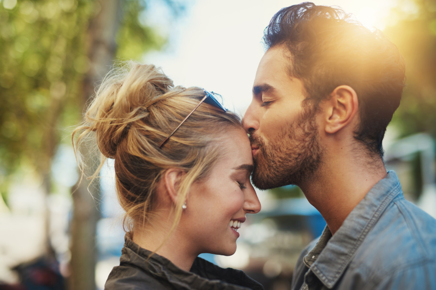 homem beijando testa da namorada em um dia de sol