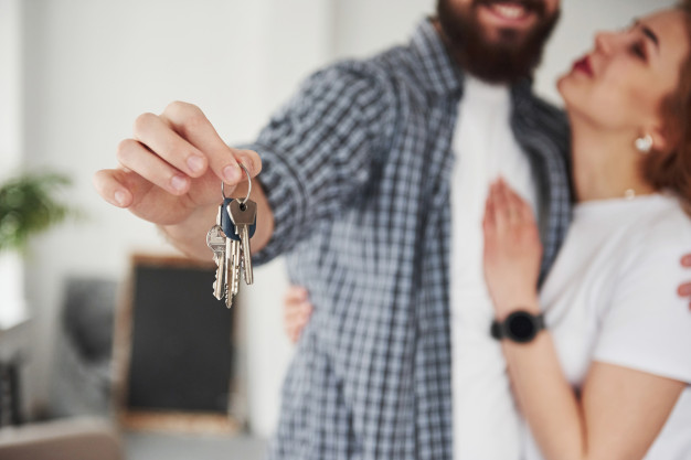 casal abraçado mostra molho de chaves de sua casa