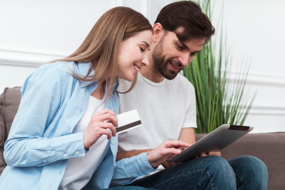 homem e mulher sentados procurando em tablet sobre qual a melhor máquina de cartão de crédito