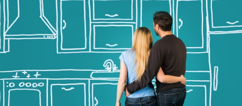 casal abraçado em frente `fundo de lousa com desenho de uma cozinha