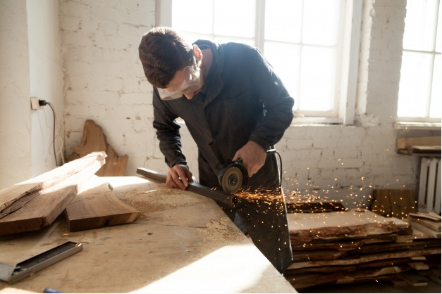trabalhador em reforma de casa antiga usa uma serra e equipamento de porteção para cortar pedaço de metal