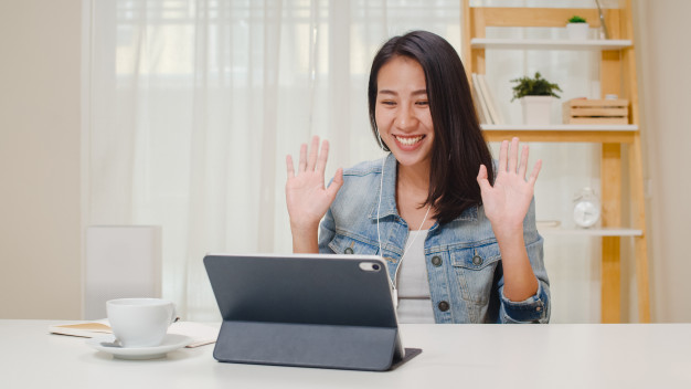 mulher sentada de frente para um laptop sorrindo com as mãos pra cima