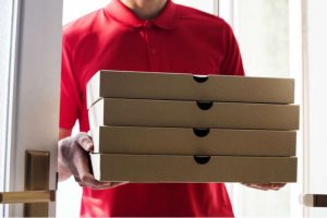 imagem ampliada de um homem de camiseta vermelha carregando caixas de pizza
