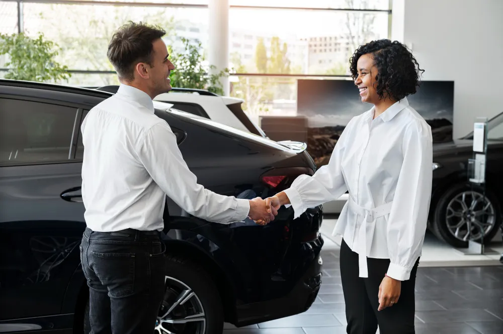 vendedor de carro e compradora apertando as mãos em negócio - financiamento de carro para negativado
