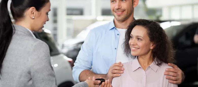 vendedora entregando as chaves de carro novo para um casal feliz - financiamento de carro para negativado