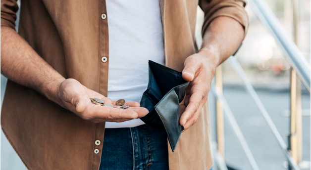imagem de corpo de homem usando camisa marrom abrindo sua carteira e coletando poucas moedas