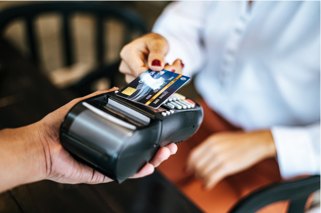 imagem aproximada de uma mulher realizando um pagamento com cartão de crédito em uma máquina
