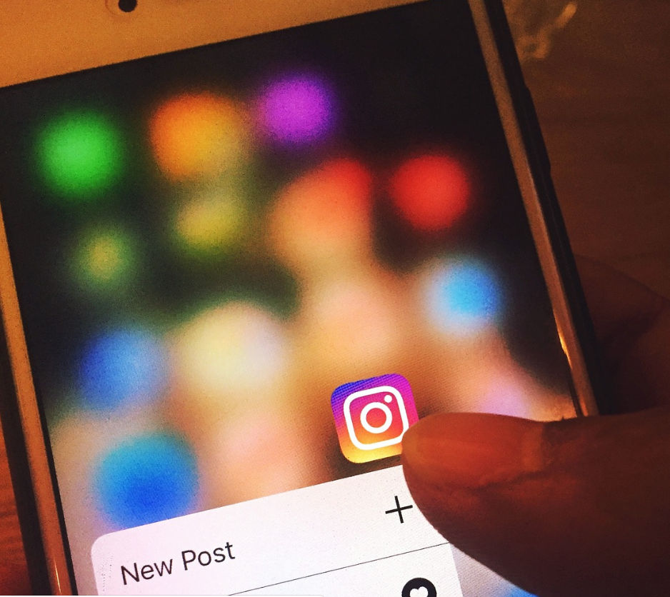 imagem ampliada de uma pessoa abrindo o aplicativo Instagram e um celular
