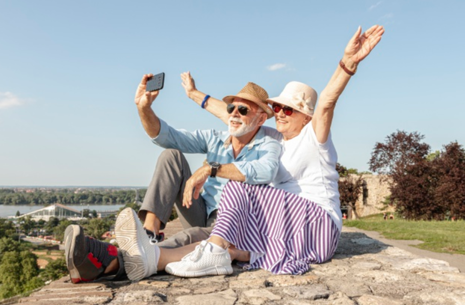 casal de idosos sentado em pedra tirando uma foto
