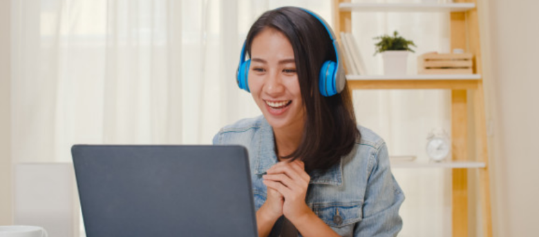 mulher assistindo vídeos sobre educação financeira em um laptop sorrindo usando um headphone