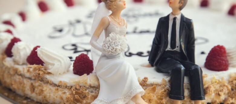 Bolo de casamento simples decorado com noivinhos sentados à beira