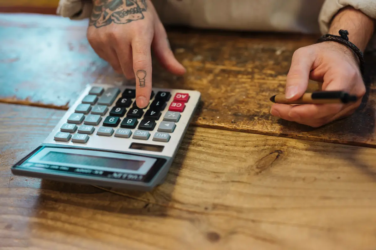 Mão usando calculadora e verificando se não caiu na malha fina imposto de renda