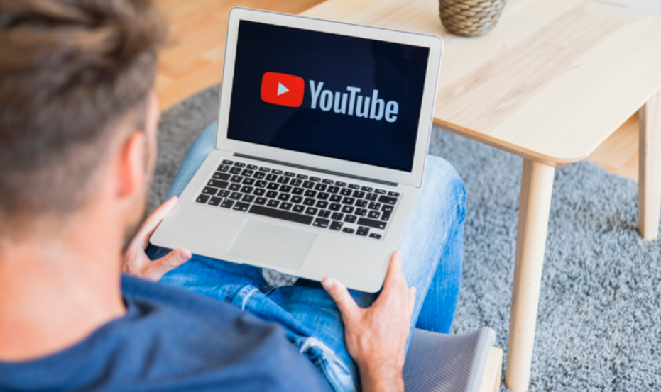 imagem de um homem sentado com seu laptop no colo enquanto entra no youtube
